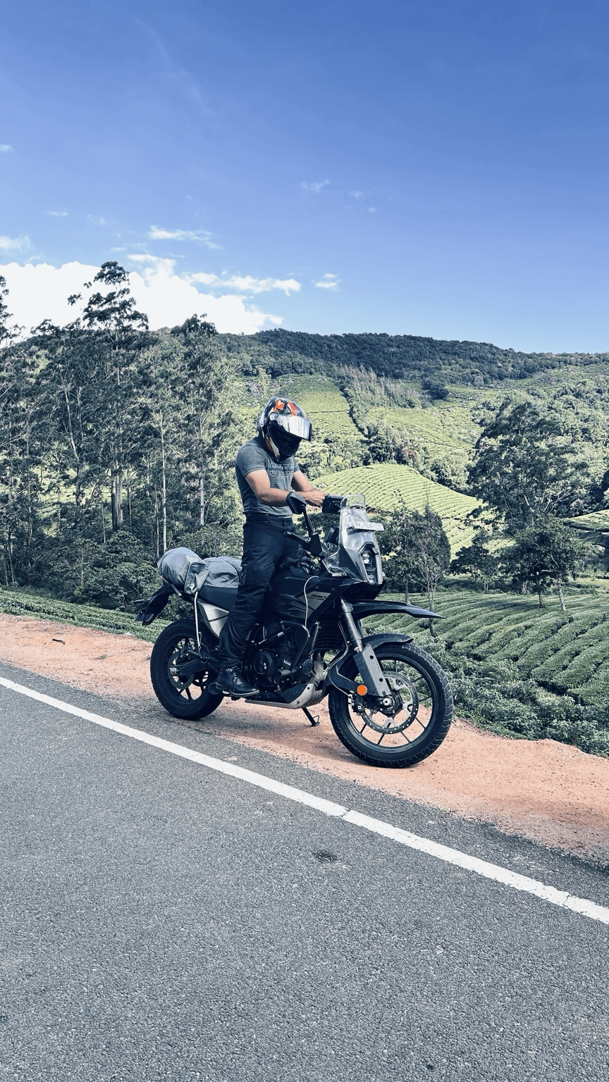 Sharan with his motorcycle during a ride through green hills